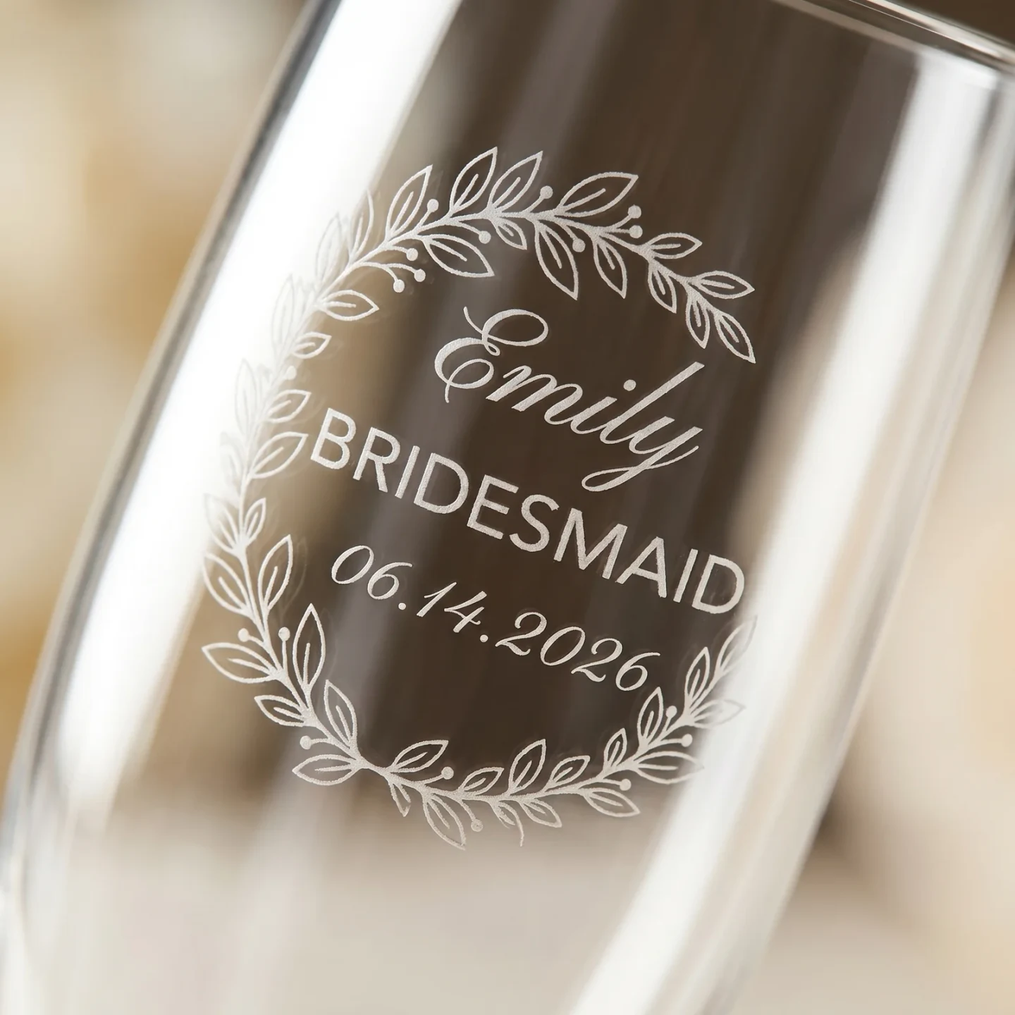 Macro closeup of the Eucalyptus Crescent Crest on a champagne flute — a soft half-moon arch of silver dollar and seeded eucalyptus above a cursive first name, the word 'Bridesmaid' in small caps, and a wedding date in italic script.