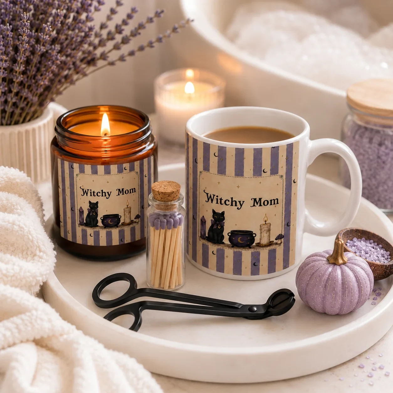 Cozy witchy gifts for her — a personalized Witchy Mom black cat mug and matching amber candle on a cream tray with matches, a wick trimmer, lavender and a lilac pumpkin.